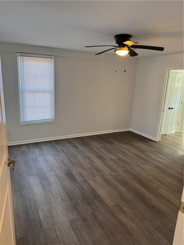 spare room featuring baseboards, dark wood finished floors, and a ceiling fan