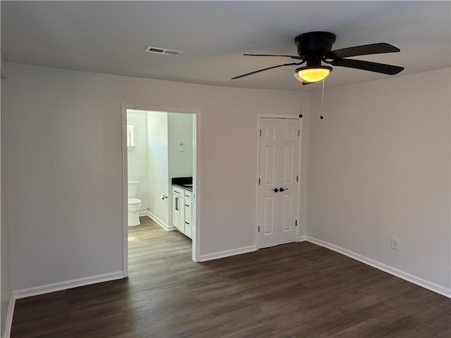 empty room with dark wood-style flooring, visible vents, ceiling fan, and baseboards