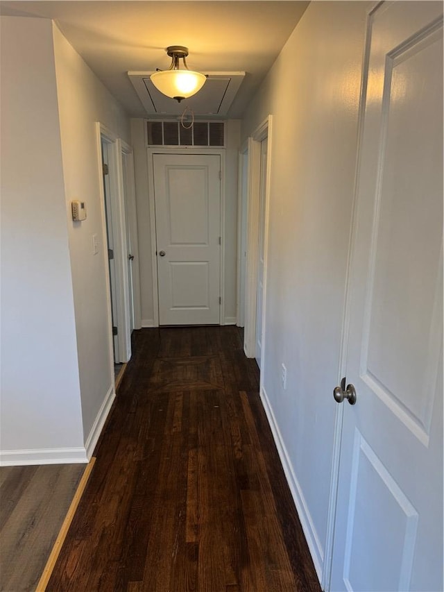 hall with visible vents, dark wood-type flooring, attic access, and baseboards