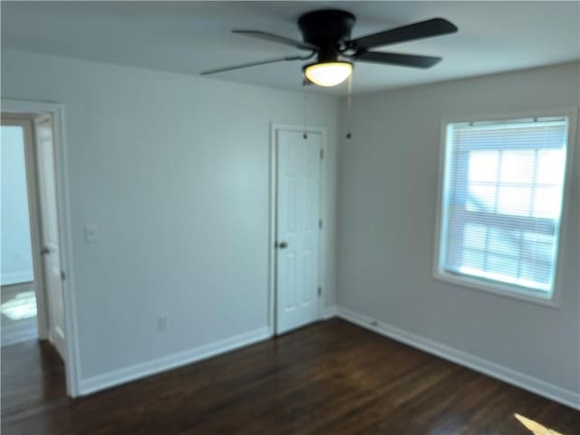 interior space with ceiling fan, a closet, baseboards, and dark wood-style flooring