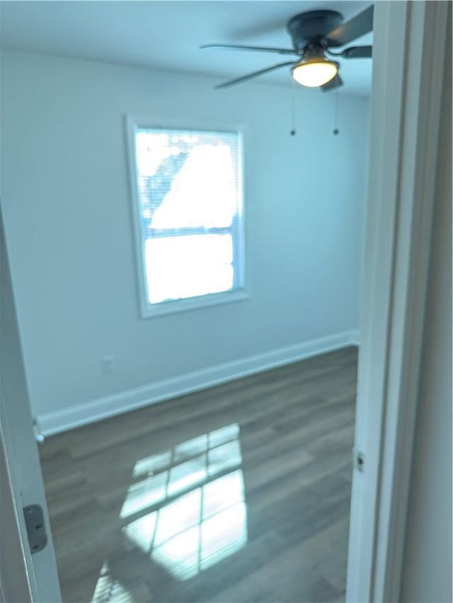 spare room featuring ceiling fan, baseboards, and wood finished floors