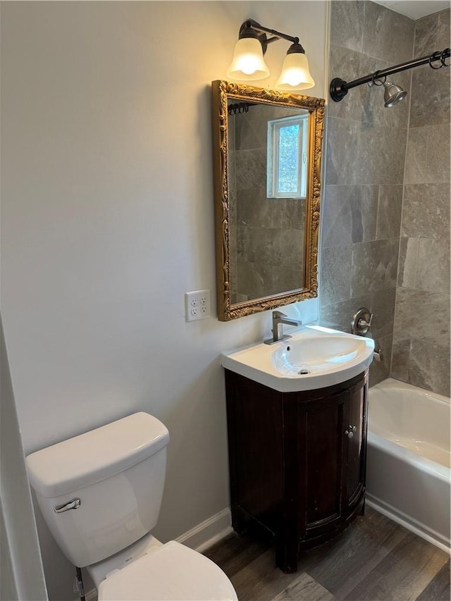 bathroom with baseboards, toilet, wood finished floors,  shower combination, and vanity