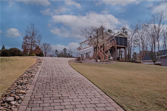 surrounding community with decorative driveway, a yard, and stairway