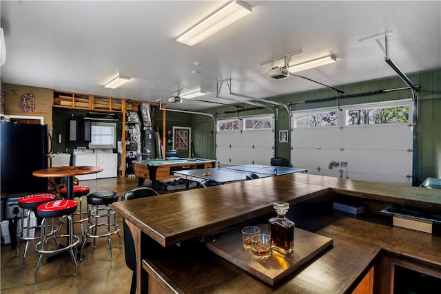 garage with a garage door opener, washer and dryer, freestanding refrigerator, and water heater