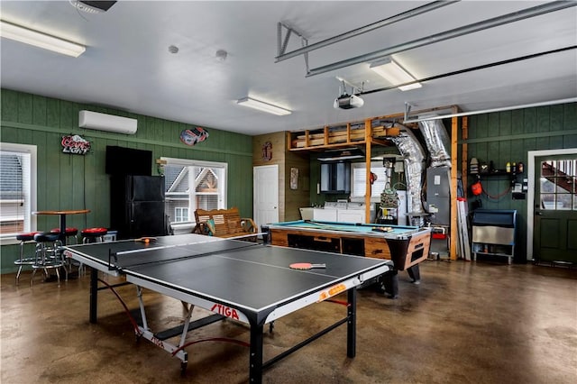 rec room featuring a garage, a healthy amount of sunlight, a wall mounted AC, and finished concrete floors