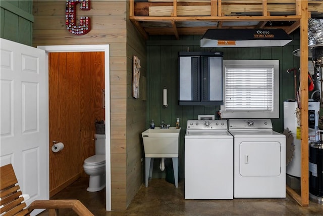 washroom with wood walls, gas water heater, and independent washer and dryer