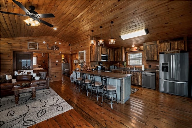 kitchen with dark countertops, appliances with stainless steel finishes, wooden walls, wooden ceiling, and a peninsula