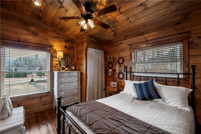 bedroom featuring vaulted ceiling, wooden ceiling, hardwood / wood-style flooring, and wooden walls