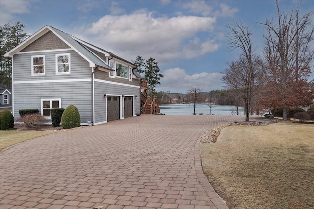 view of property exterior featuring a garage, decorative driveway, and a water view