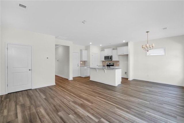 unfurnished living room with baseboards, a sink, wood finished floors, and a chandelier