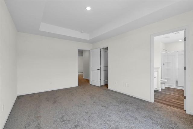 unfurnished bedroom with a raised ceiling, baseboards, and carpet