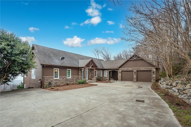 view of front of house with an attached garage, stone siding, driveway, and a shingled roof