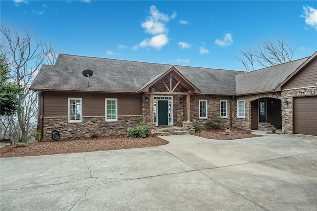 view of front facade featuring stone siding, roof with shingles, an attached garage, and concrete driveway