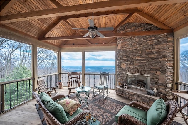 sunroom / solarium featuring lofted ceiling with beams, an outdoor stone fireplace, and wood ceiling