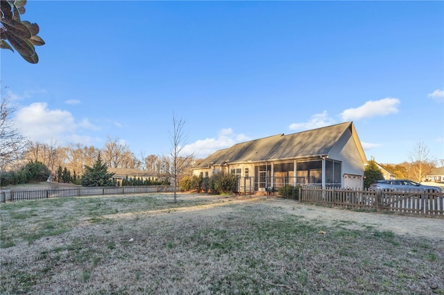 back of property featuring a sunroom, fence, and a lawn