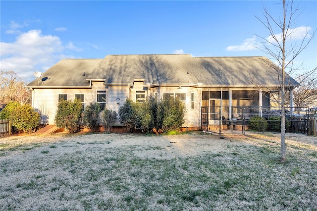 rear view of house with a lawn, fence, and a sunroom