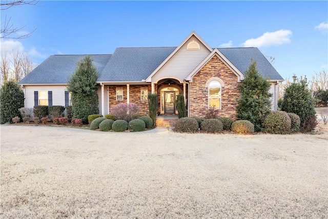 view of front of home with stone siding and roof with shingles