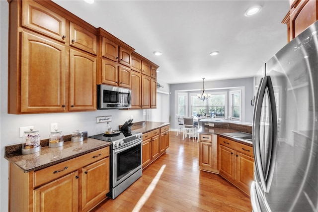 kitchen featuring recessed lighting, appliances with stainless steel finishes, brown cabinetry, a chandelier, and light wood-type flooring