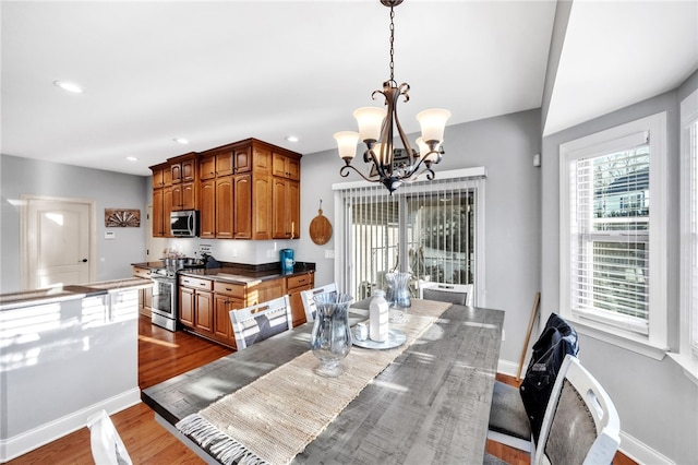 dining area featuring dark wood-style flooring, an inviting chandelier, and baseboards