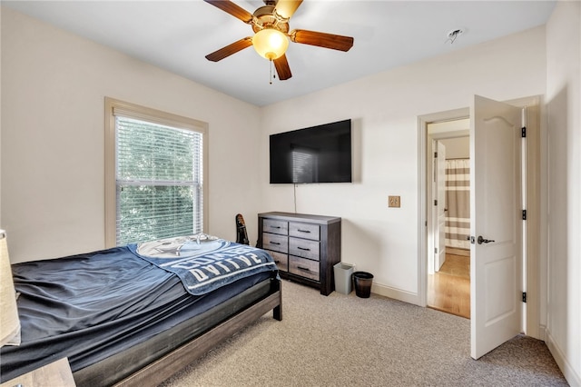 bedroom with a ceiling fan, light carpet, and baseboards