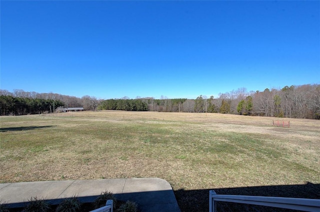 view of yard with a rural view and a view of trees