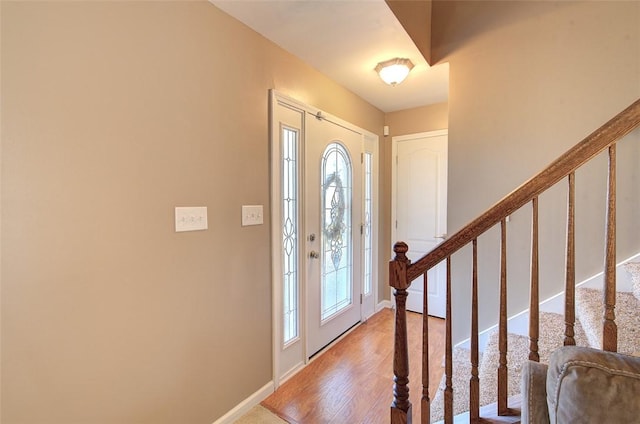 foyer entrance featuring light wood-style flooring, stairs, and baseboards