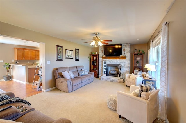 living area featuring light carpet, a large fireplace, ceiling fan, and baseboards