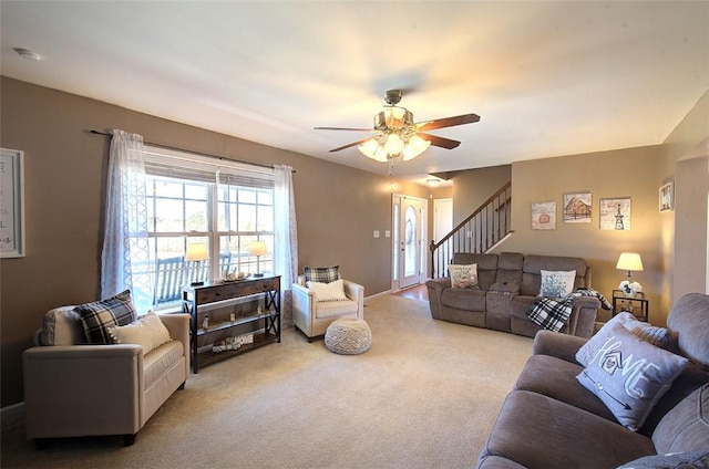 carpeted living room featuring a ceiling fan and stairs