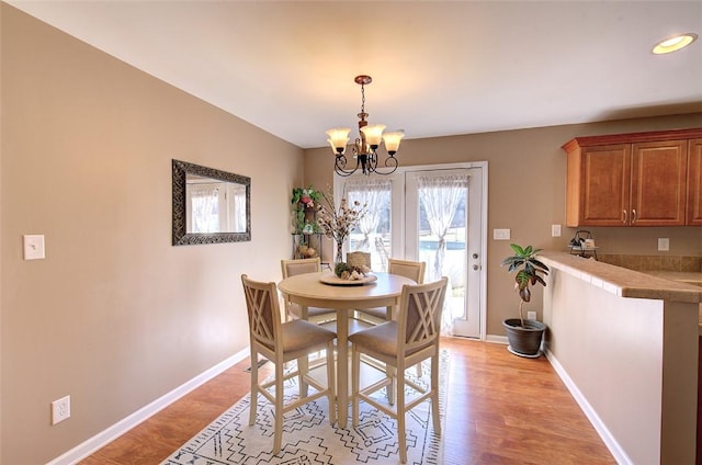 dining space featuring light wood-type flooring, baseboards, and a notable chandelier