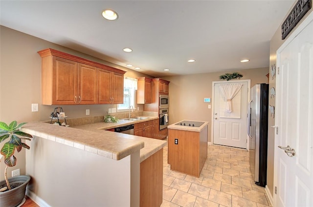 kitchen with a center island, a peninsula, light countertops, stainless steel appliances, and a sink