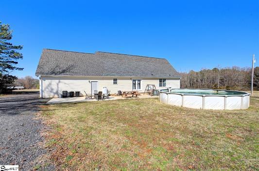 rear view of house featuring a lawn, a patio area, and an outdoor pool