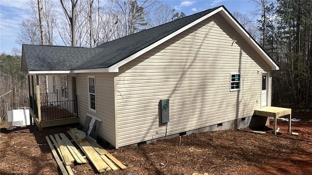 view of side of property featuring a shingled roof and crawl space