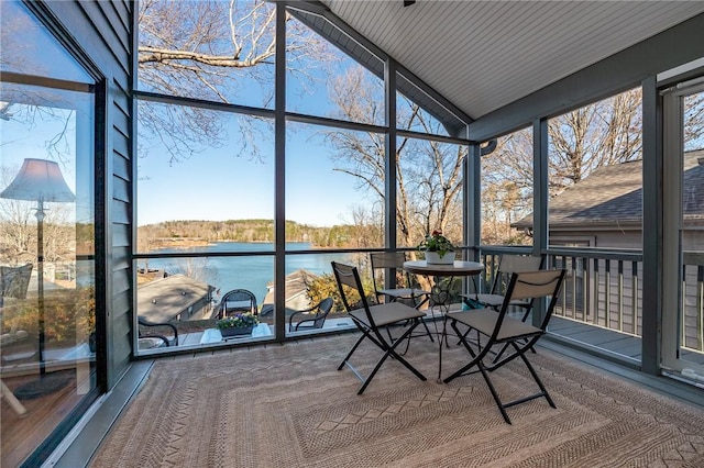 unfurnished sunroom featuring lofted ceiling and a water view