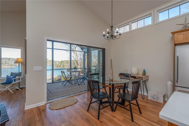 dining space featuring light wood-style floors, high vaulted ceiling, and an inviting chandelier