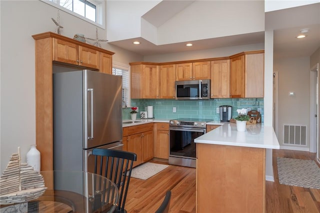 kitchen with stainless steel appliances, light countertops, visible vents, and a peninsula