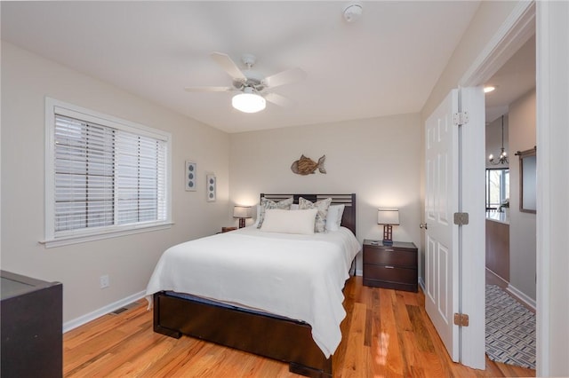 bedroom featuring a ceiling fan, baseboards, multiple windows, and light wood finished floors