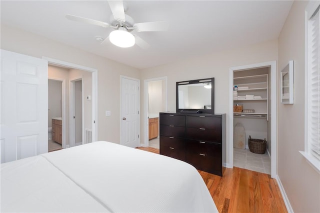 bedroom featuring light wood-style floors, ensuite bath, visible vents, and a walk in closet