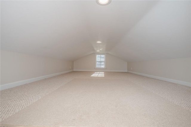 additional living space with lofted ceiling, baseboards, and light colored carpet