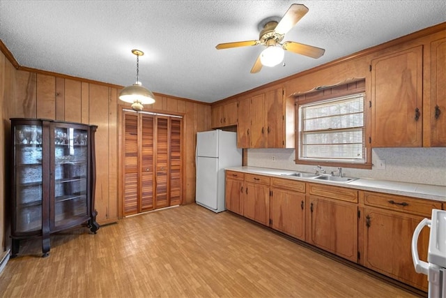 kitchen with brown cabinets, freestanding refrigerator, light countertops, and a sink