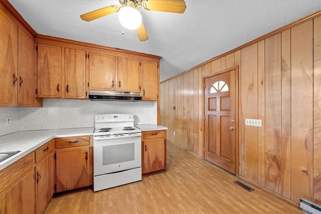 kitchen featuring electric stove, light countertops, visible vents, light wood-style floors, and under cabinet range hood