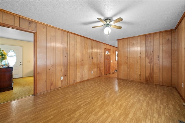 empty room featuring a textured ceiling, ornamental molding, and wood finished floors