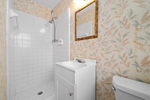 full bath featuring tiled shower, vanity, toilet, and wallpapered walls