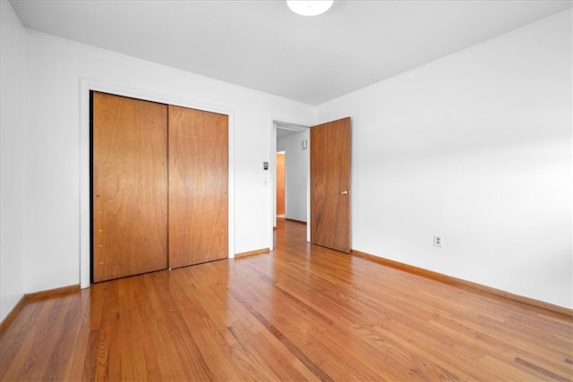 unfurnished bedroom featuring a closet, baseboards, and wood finished floors