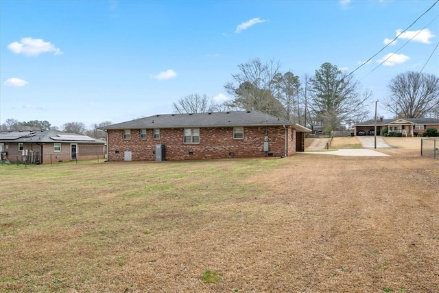 rear view of house with crawl space, brick siding, a yard, and driveway