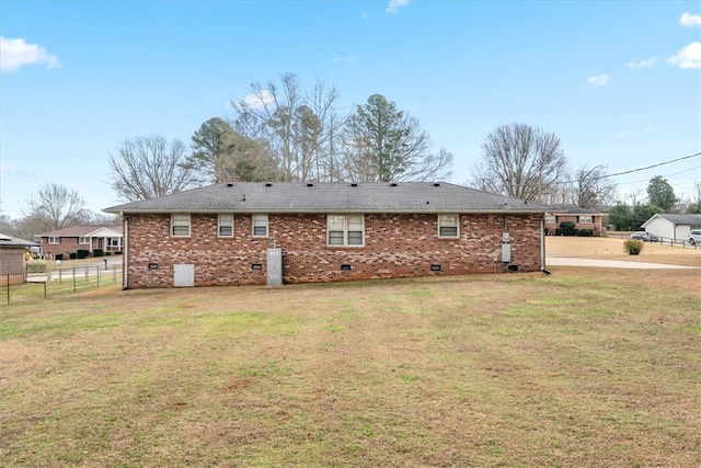 rear view of house featuring crawl space, brick siding, fence, and a lawn