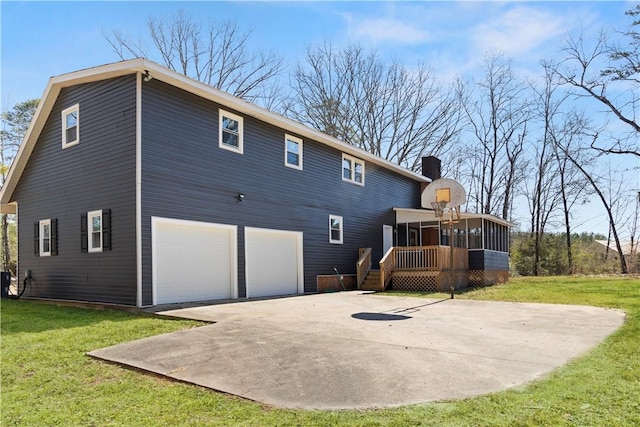 rear view of house with a garage, a yard, a chimney, and a sunroom