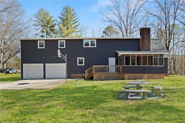 rear view of house featuring a sunroom, driveway, an attached garage, and a lawn