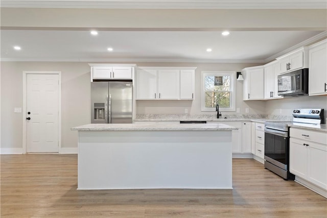 kitchen featuring stainless steel appliances, a kitchen island, white cabinetry, light wood finished floors, and crown molding