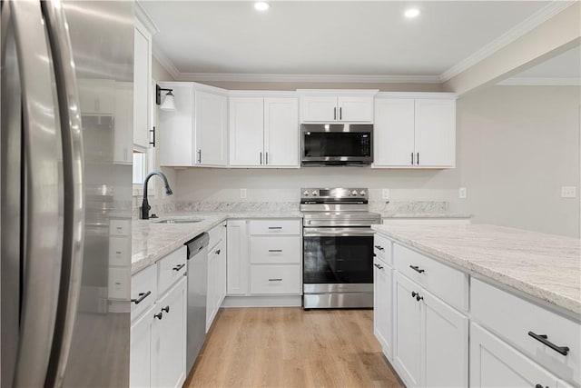 kitchen with appliances with stainless steel finishes, light stone countertops, crown molding, light wood-type flooring, and a sink