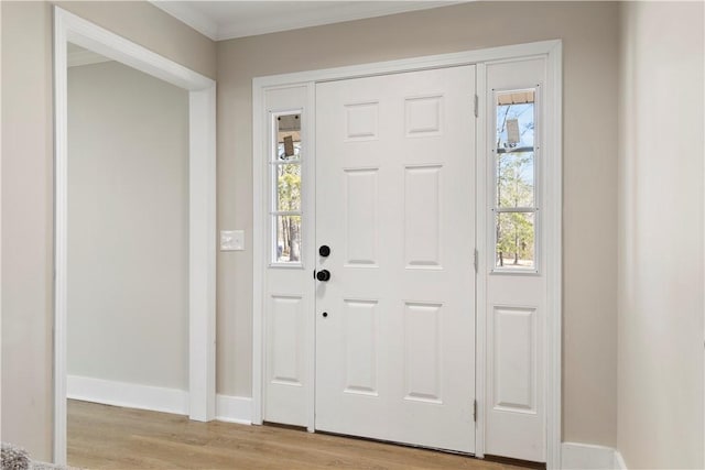 entryway featuring baseboards, crown molding, and light wood-style floors